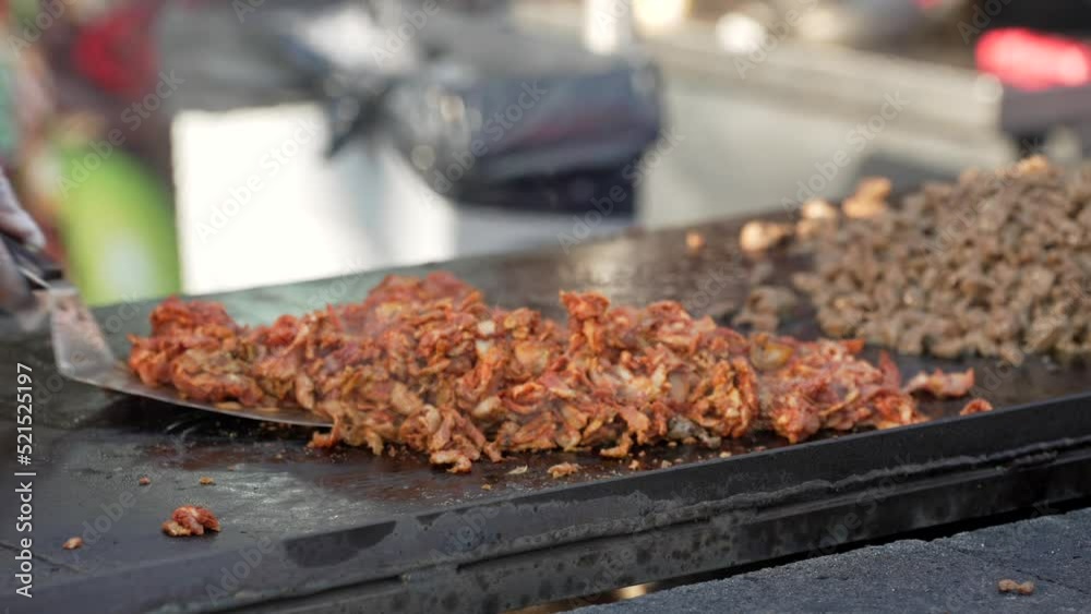 This close up, slow motion video shows the hands of a chef chopping al pastor taco meet and cooking it on our outdoor grill.