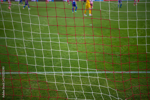 Football goal net during the game. Blurred players in background. Soccer background blurred photo  focus on net.