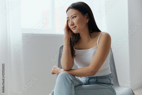 Panic attack. Upset tormented tanned beautiful young Asian woman touching head feel headache at home interior living room. Injuries Poor health Illness concept. Cool offer Banner