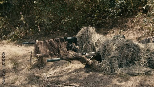 Snipers in an ambush in the grass, disguised as terrain on an anti-terrorist operation with sniper rifles, shooting at the enemy. Footage of military operations. Soldiers in full gear. Cinematic shot photo