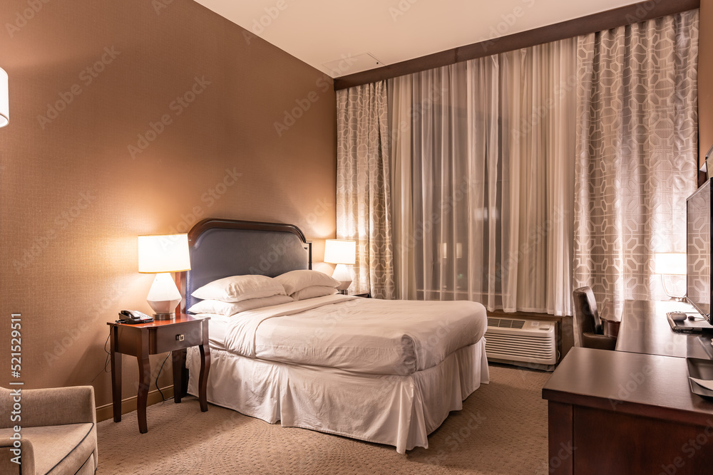 Interior evening photo of a typical US hotel room with a king size bed and chair. Interior evening photo of a typical US hotel room with a king size bed and chair.
