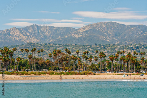 Santa Barbara beach and ocean view, palm trees, mountains, and cloudy sky on background