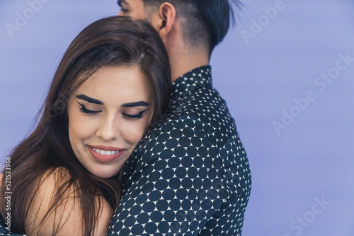 Young woman with dark long hair smiling hugging her boyfriend leaning on his shoulder. Happy couple. Studio shot. High quality photo