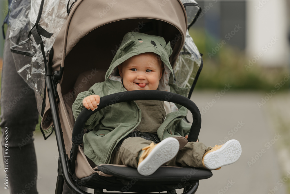 A female toddler is sitting in the stroller on a cloudy day.
