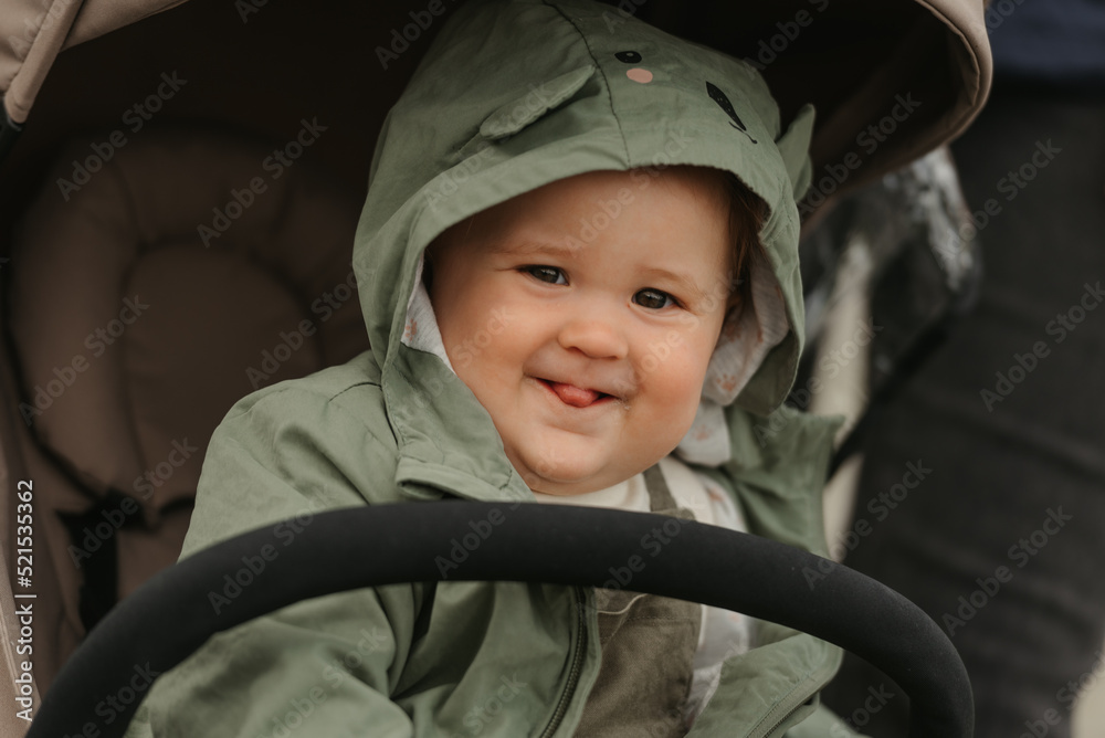 A female toddler is sitting in the stroller on a cloudy day.