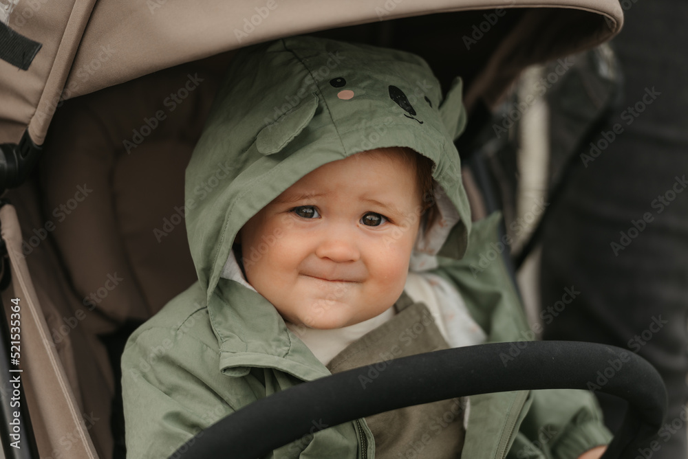 A female toddler is sitting in the stroller on a cloudy day.