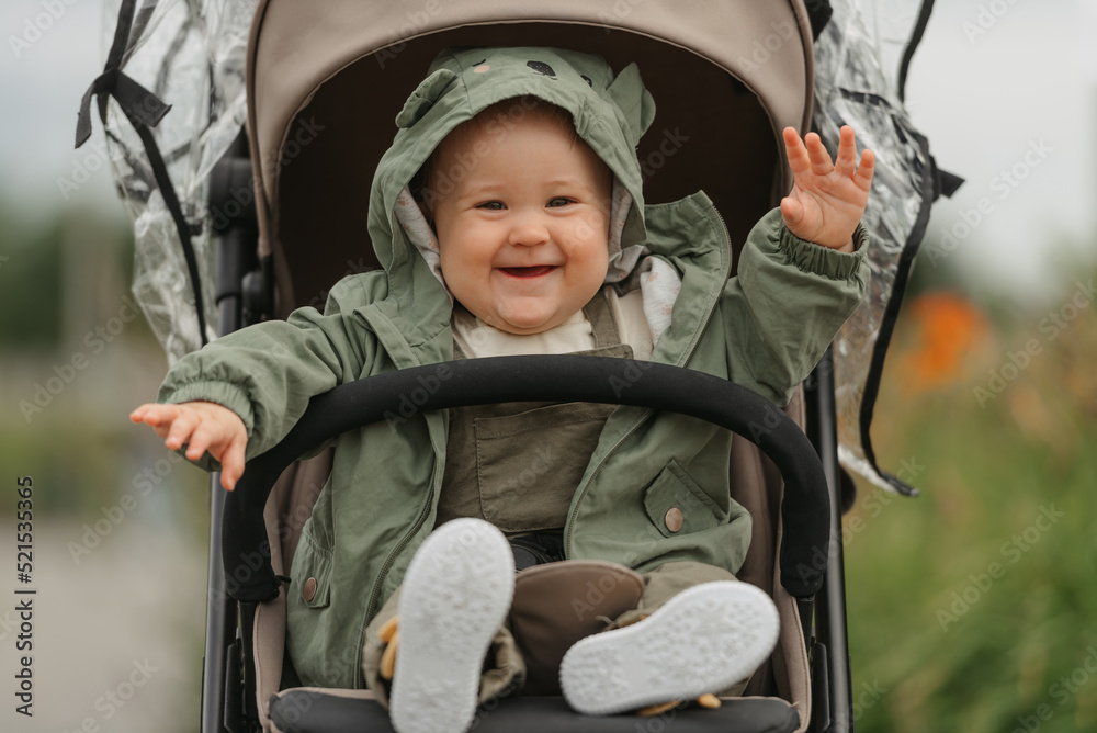 A female toddler is sitting in the stroller on a cloudy day.