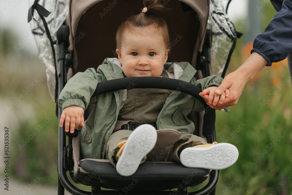 A female toddler is sitting in the stroller on a cloudy day.