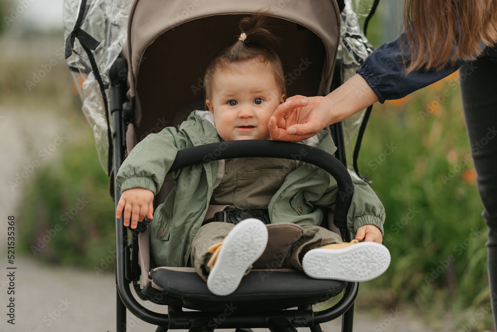 A female toddler is sitting in the stroller on a cloudy day.