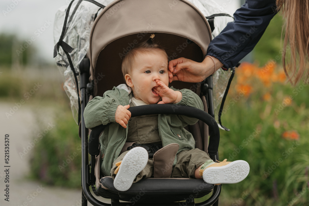 A female toddler is sitting in the stroller on a cloudy day.