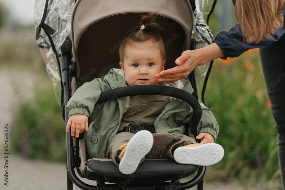 A female toddler is sitting in the stroller on a cloudy day.