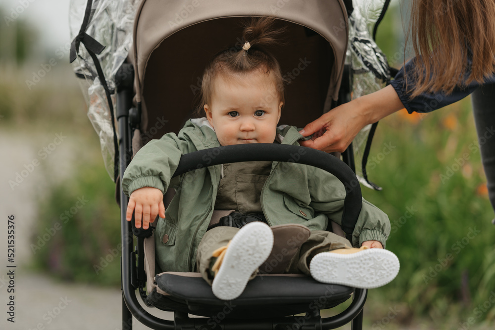 A female toddler is sitting in the stroller on a cloudy day.