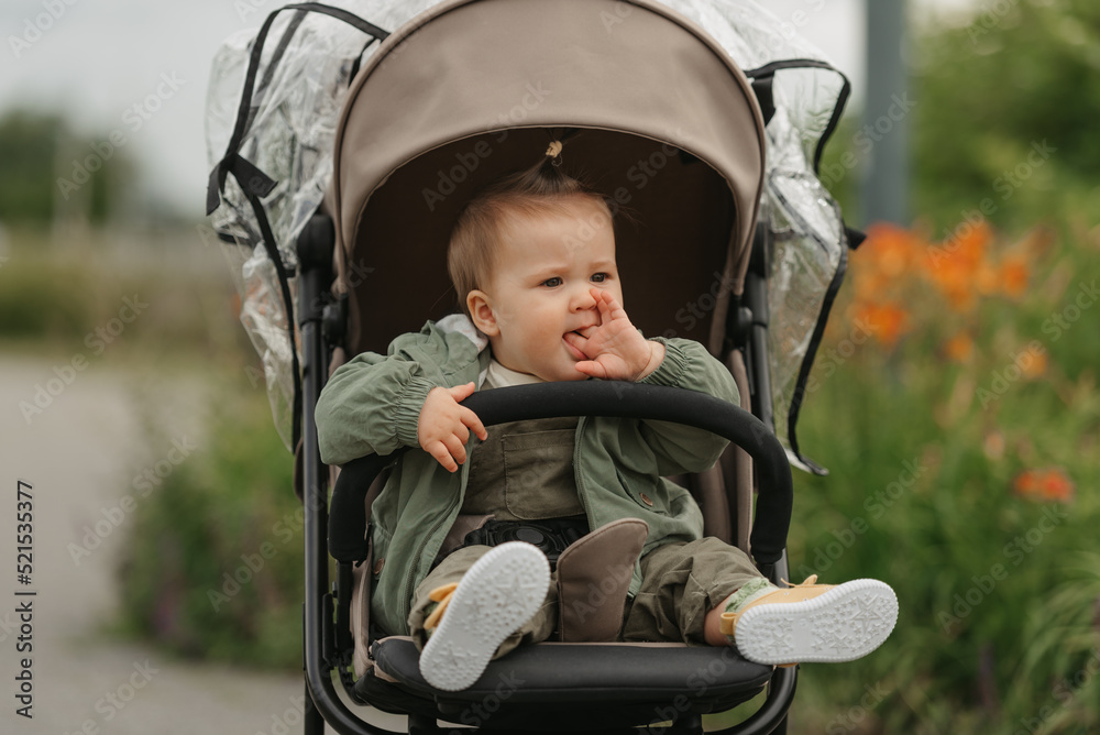 A female toddler is sitting in the stroller on a cloudy day. A female toddler is sitting in the stroller on a cloudy day.