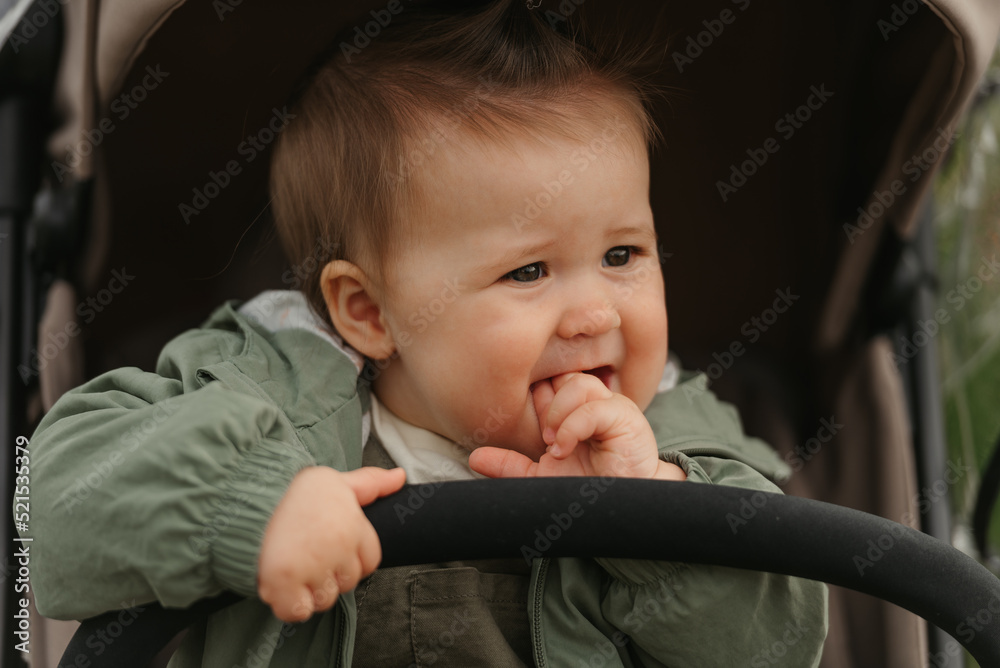 A female toddler is sitting in the stroller on a cloudy day.