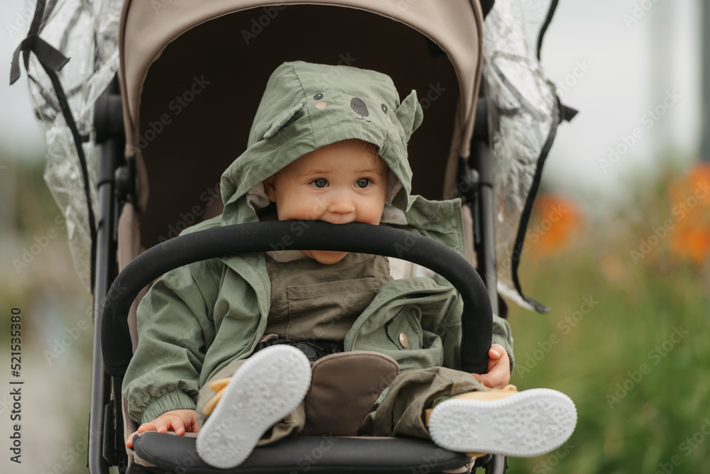 A female toddler is sitting in the stroller on a cloudy day.