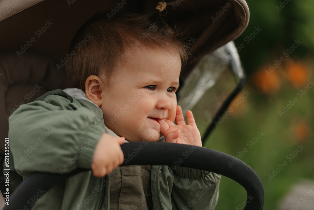A female toddler is sitting in the stroller on a cloudy day.