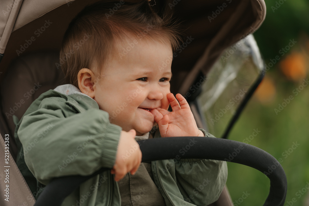 A female toddler is sitting in the stroller on a cloudy day.