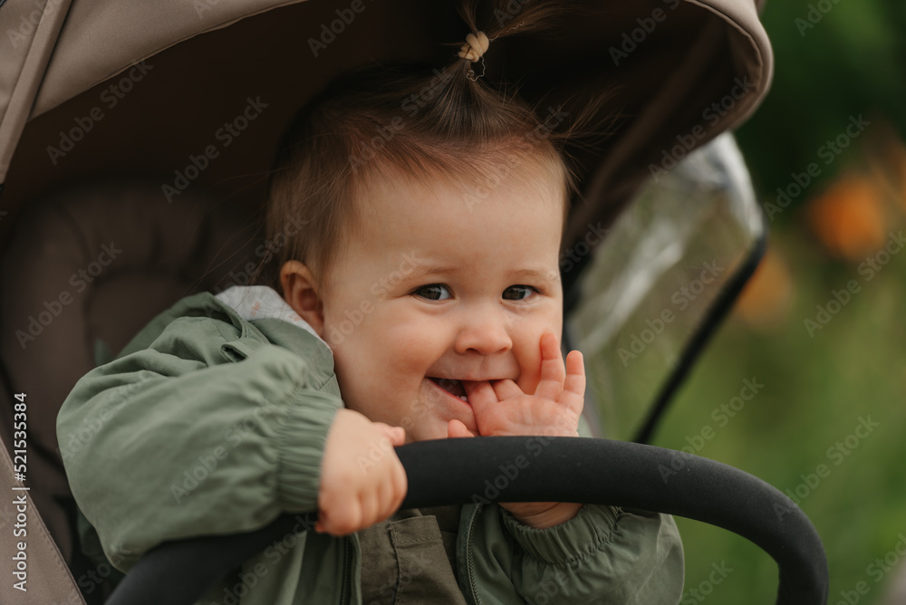 A female toddler is sitting in the stroller on a cloudy day.