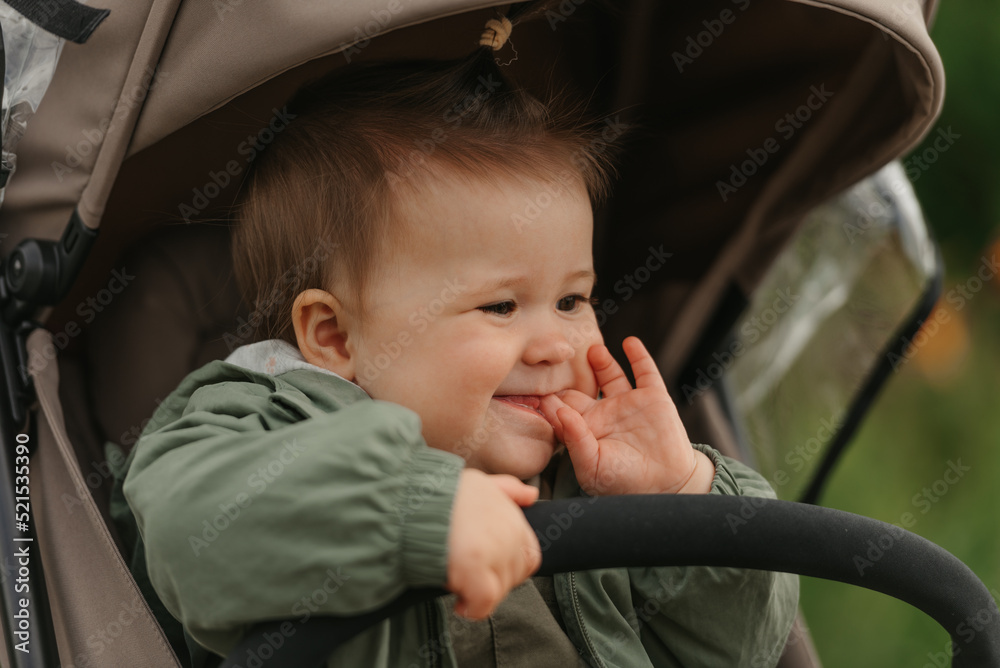A female toddler is sitting in the stroller on a cloudy day.