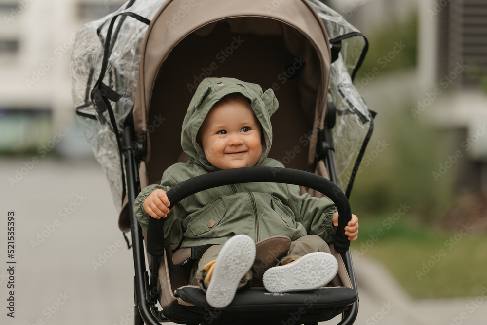 A female toddler is sitting in the stroller on a cloudy day.