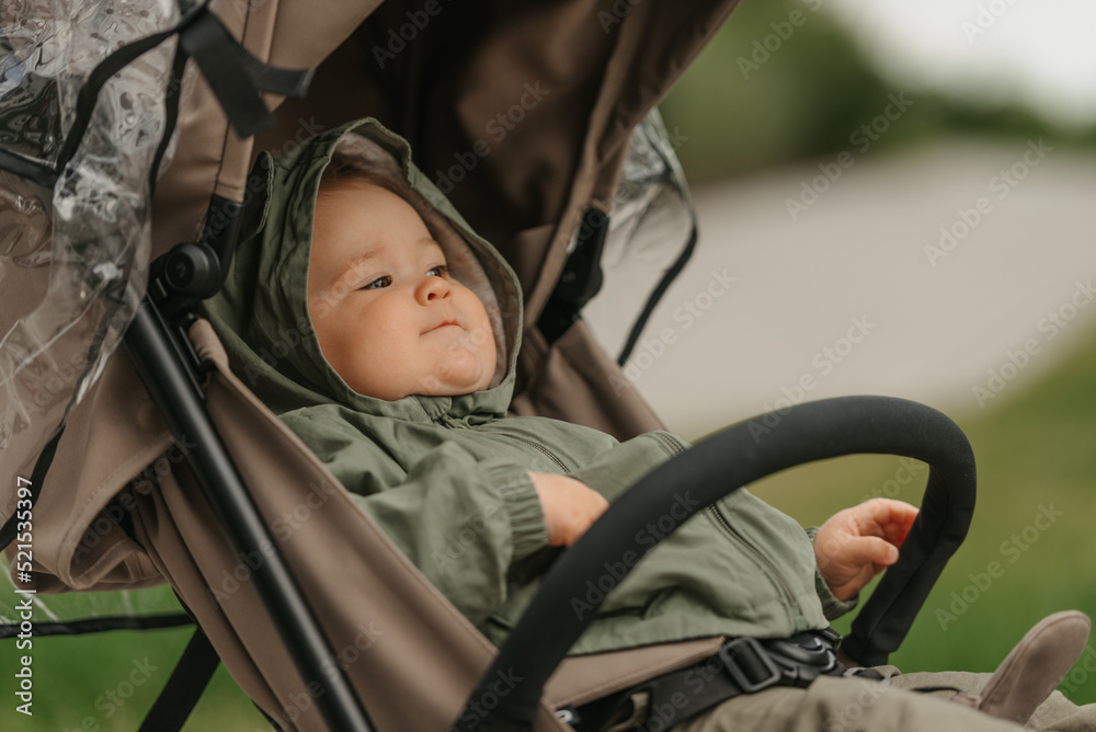 A female toddler is sitting in the stroller on a cloudy day.