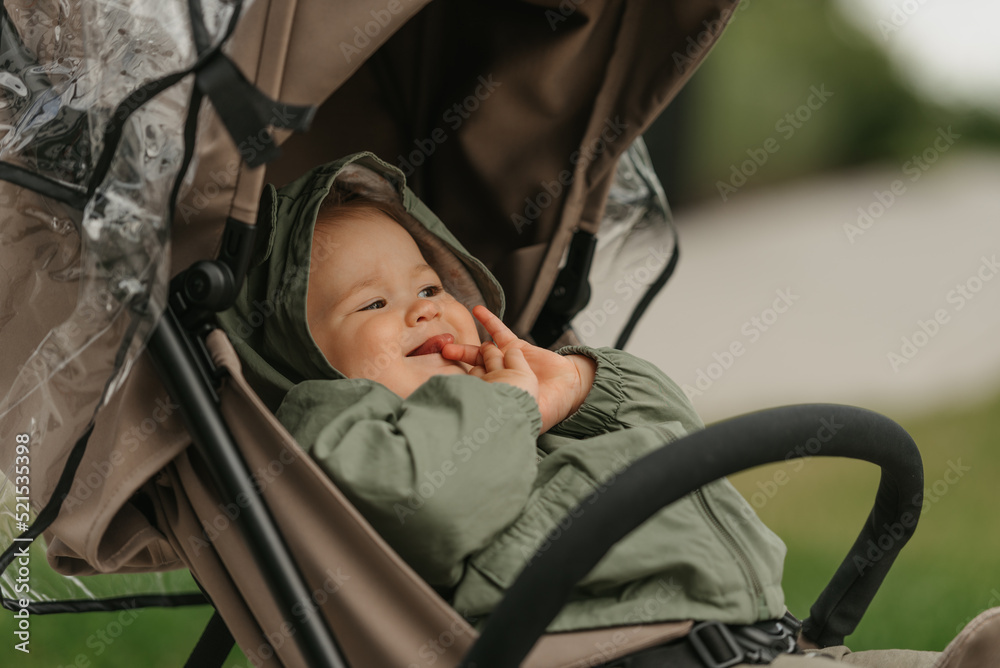 A female toddler is sitting in the stroller on a cloudy day.