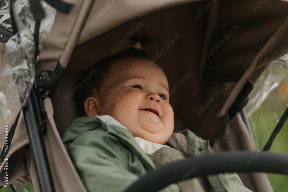 A female toddler is sitting in the stroller on a cloudy day.