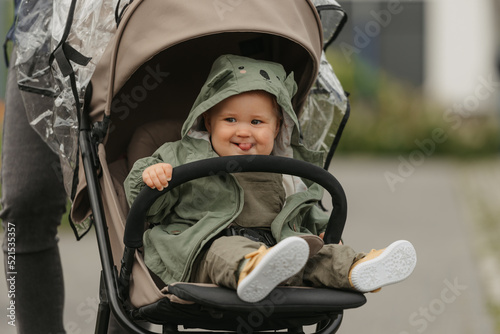 Obraz na płótnie A female toddler is sitting in the stroller on a cloudy day. w salonie