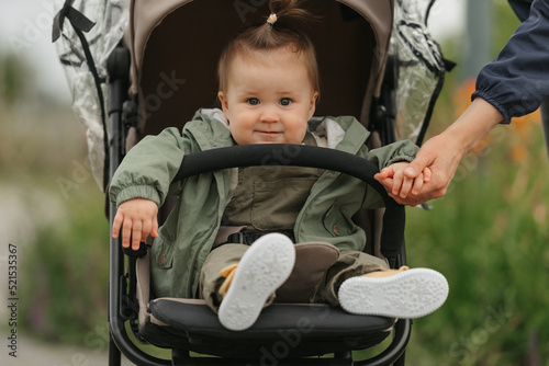 Obraz na płótnie A female toddler is sitting in the stroller on a cloudy day. w salonie