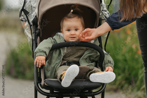 Obraz na płótnie A female toddler is sitting in the stroller on a cloudy day. w salonie