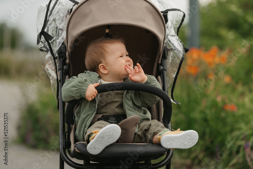 Obraz na płótnie A female toddler is sitting in the stroller on a cloudy day. w salonie