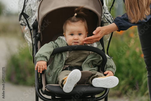 A female toddler is sitting in the stroller on a cloudy day.