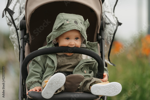 Obraz na płótnie A female toddler is sitting in the stroller on a cloudy day. w salonie
