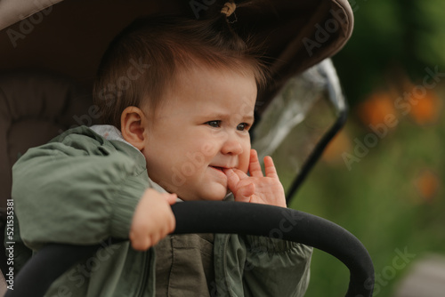 Obraz na płótnie A female toddler is sitting in the stroller on a cloudy day. w salonie