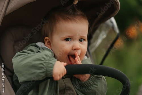 Obraz na płótnie A female toddler is sitting in the stroller on a cloudy day. w salonie
