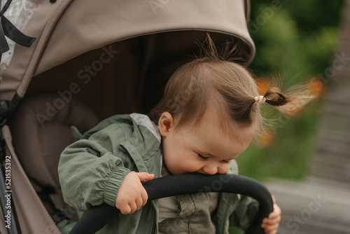Obraz na płótnie A female toddler is sitting in the stroller on a cloudy day. w salonie
