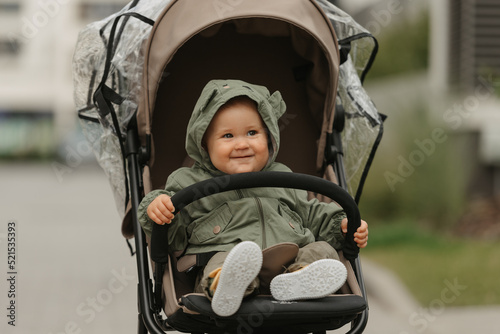 Obraz na płótnie A female toddler is sitting in the stroller on a cloudy day. w salonie