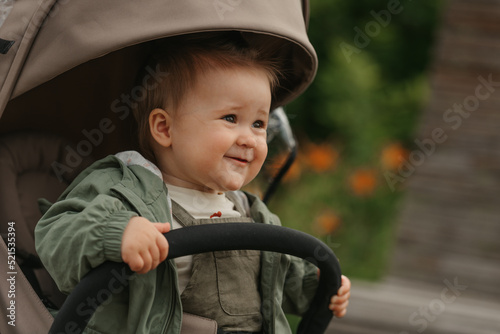 Obraz na płótnie A female toddler is sitting in the stroller on a cloudy day. w salonie