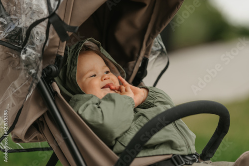 Obraz na płótnie A female toddler is sitting in the stroller on a cloudy day. w salonie