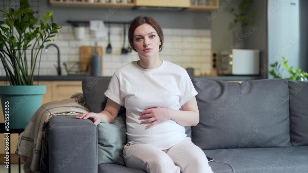 Portrait Young pregnant woman patient consults online with doctor on video call listens to advice appointment looking at camera sitting at home on sofa. Remote meeting consultation. View webcam screen Portrait Young pregnant woman patient consults online with doctor on video call listens to advice appointment looking at camera sitting at home on sofa. Remote meeting consultation. View webcam screen