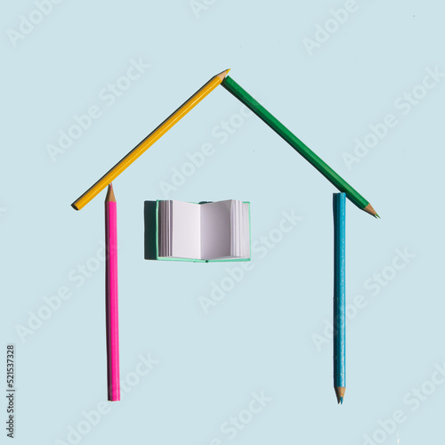 Creative back to school concept. Colorful composition with pencils and book as window on pastel bright blue background. Minimalistic education idea.