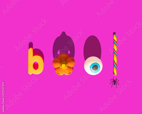 Halloween boo concept. Scary pumpkin, eye ball, candy and spider on pink background. Minimalistic holiday composition.