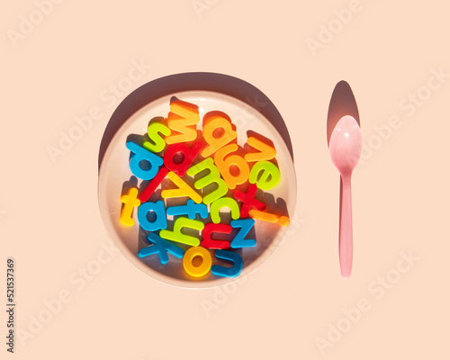 Minimalistic education idea. Creative back to school concept. Colorful composition with letters, plate and spoon on pastel bright pink background.