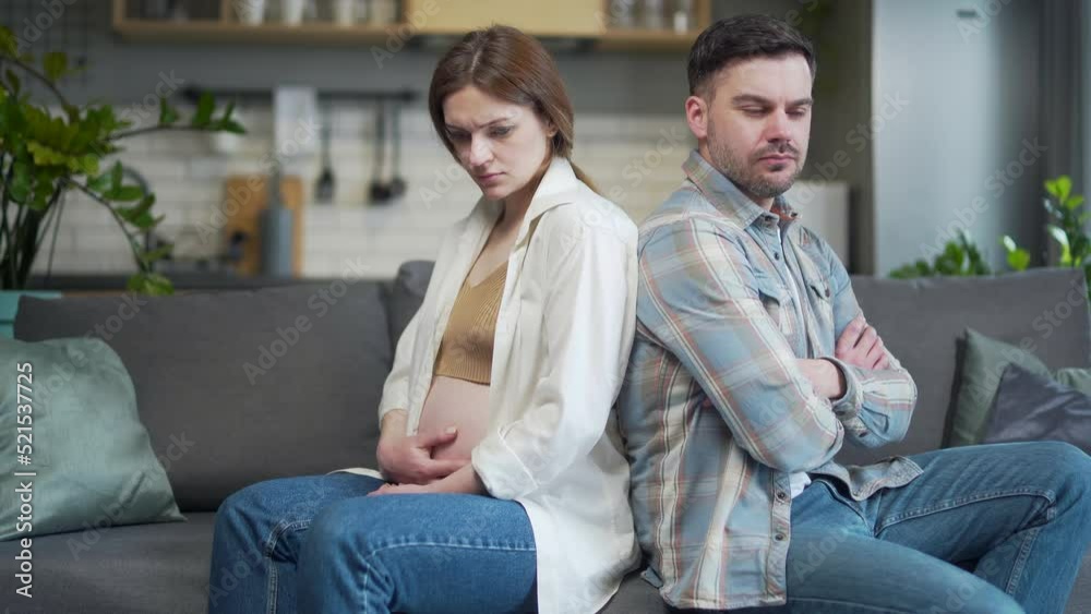 беременная пара сидит на диване и разговаривает