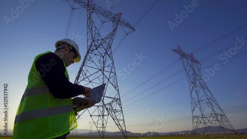 Electrical Towers and working engineer.
Engineer examining and working on computer in front of electrical towers.
