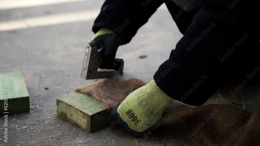 Laying the floor. Clip. A man makes a special fiber for insulation of floors in houses with a stapler.