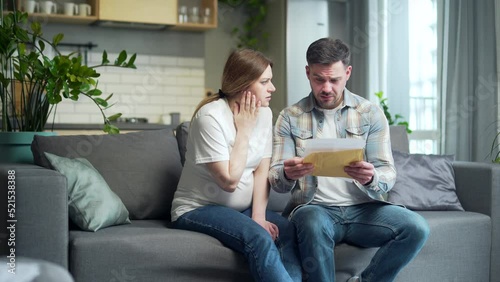 Upset Worried couple, man and pregnant woman at home, open envelope received a letter read with bad news, notice from bank reading loan denied worry with analysis results statement approval photo