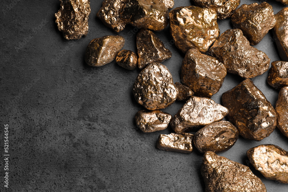 Pile of gold nuggets on grey table, flat lay. Space for text Pile of gold nuggets on grey table, flat lay. Space for text