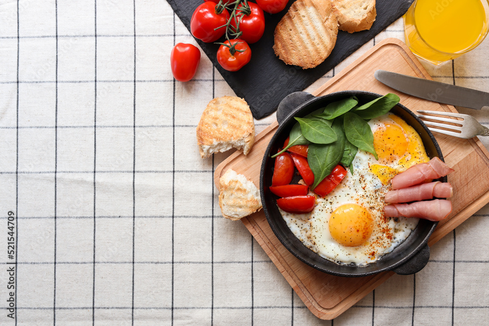 Delicious fried eggs with spinach, tomatoes and ham served on table, flat lay. Space for text Delicious fried eggs with spinach, tomatoes and ham served on table, flat lay. Space for text