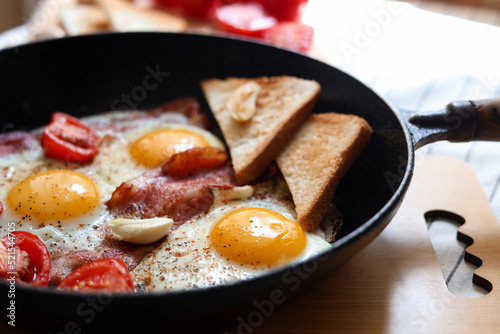 Delicious fried eggs with bacon and tomatoes in pan  closeup